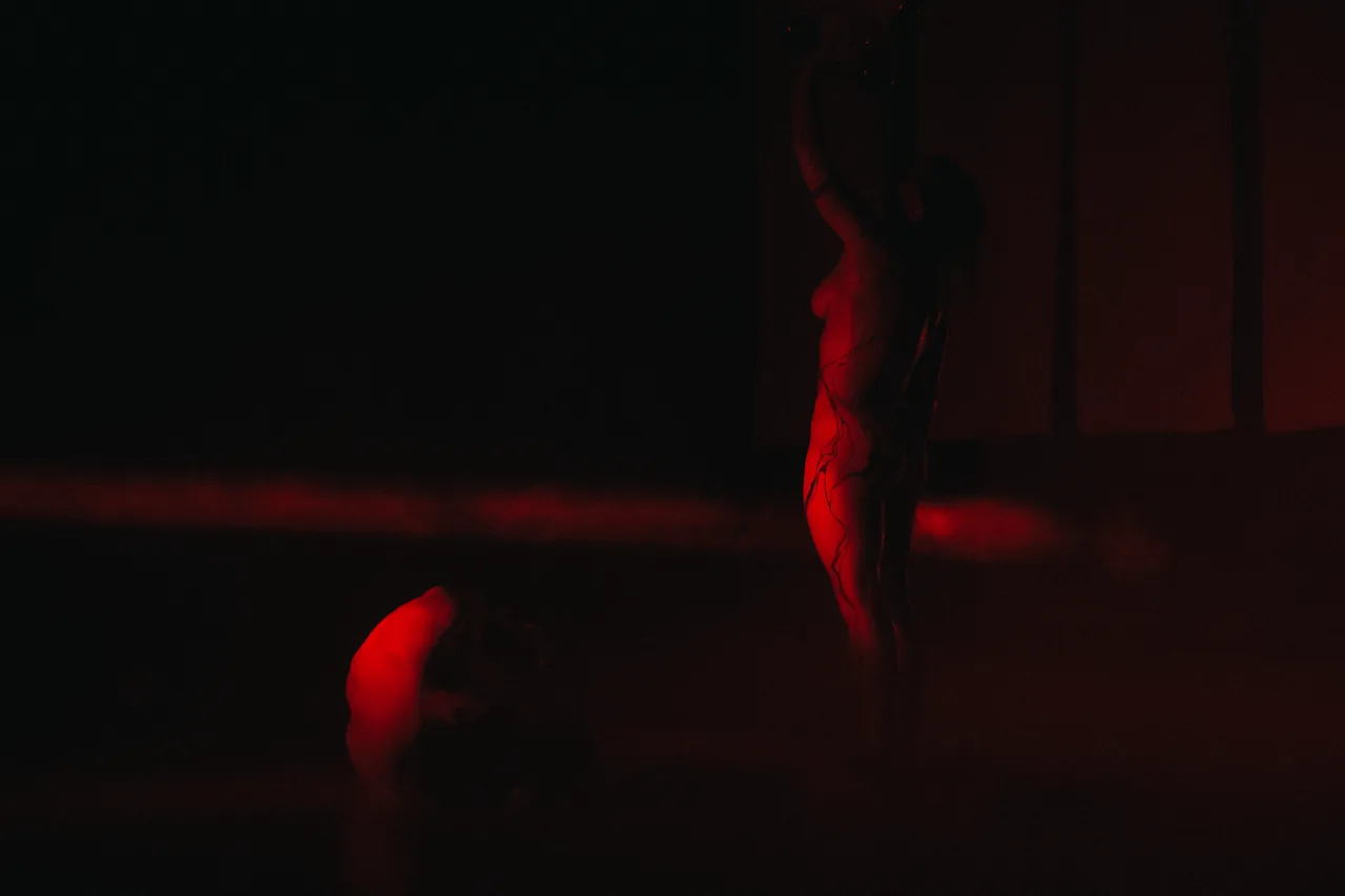 Dos intérpretes bajo iluminación roja en un escenario oscuro — Abisal