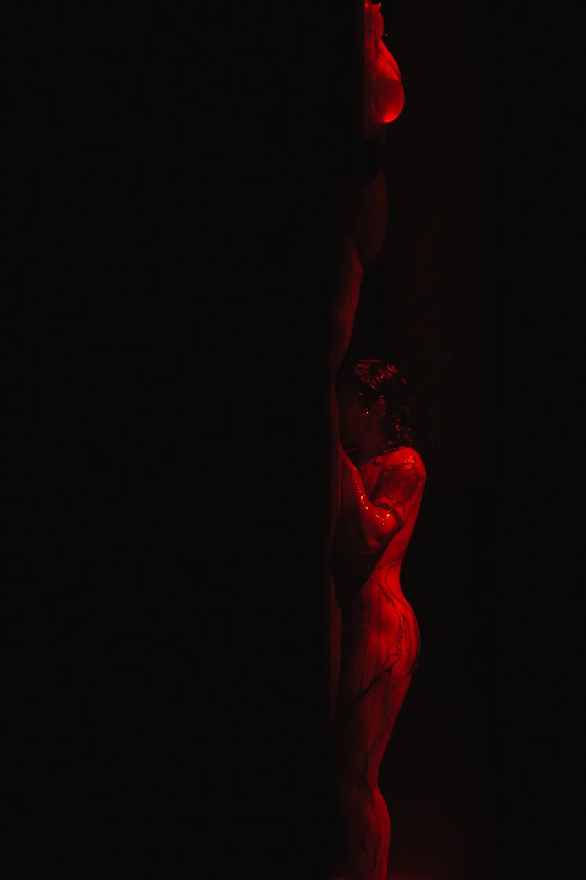Dos figuras iluminadas parcialmente en rojo en la oscuridad — Abisal