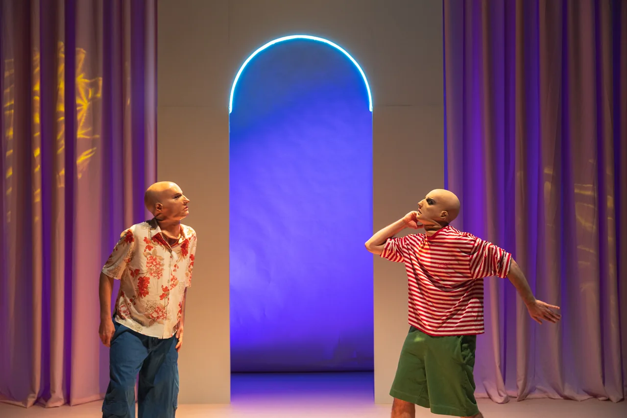 Dos intérpretes conversando ante una puerta iluminada en azul — Arreglos Florales, Corporación Morritos