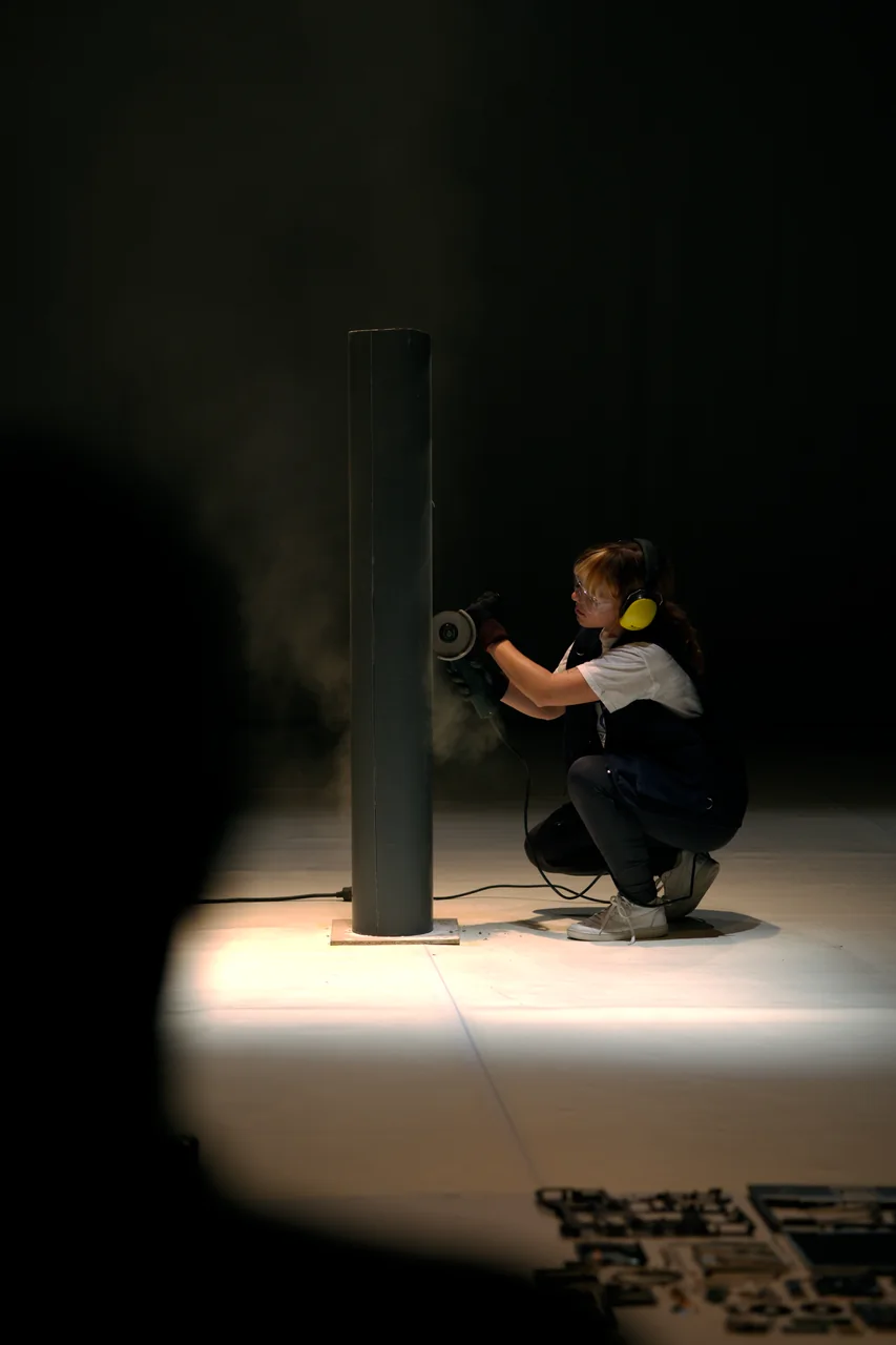 Intérprete agachado junto a una columna iluminada — Ese Otro Lugar